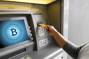 close up of woman hand inserting bank card to bitcoin atm machine with bitcoin icon on screen